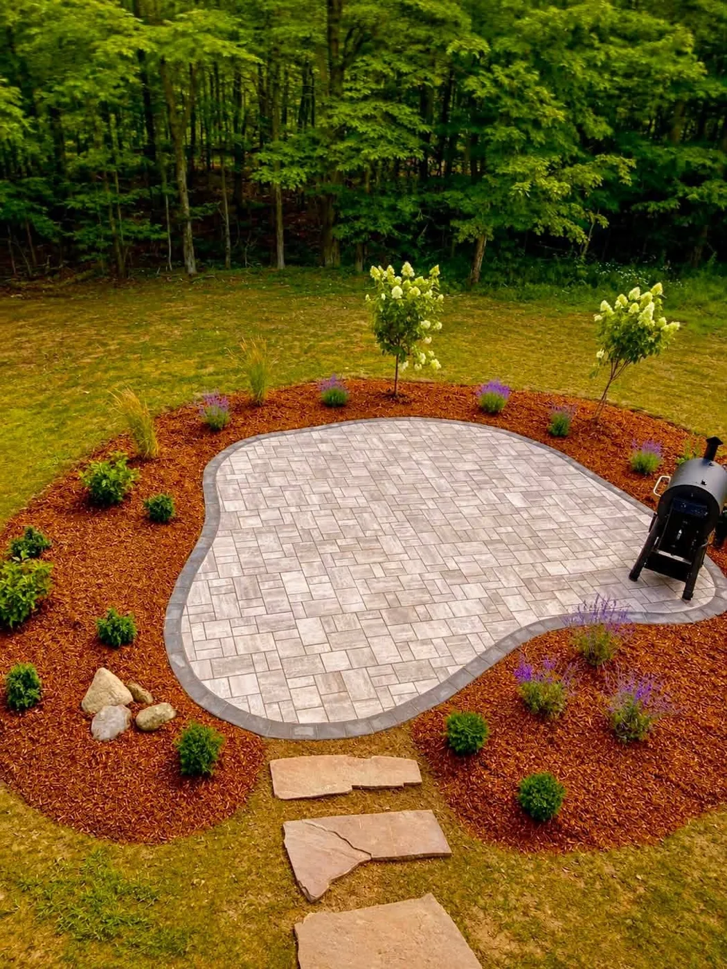 Finished paver patio with charcoal border, new plantings, mulch beds, and a stepping stone path