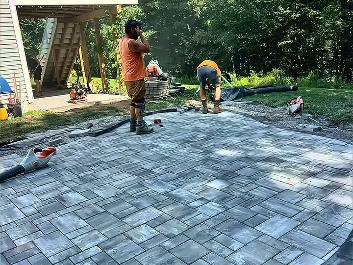 Up North Scapes crew setting pavers by hand on a rounded patio