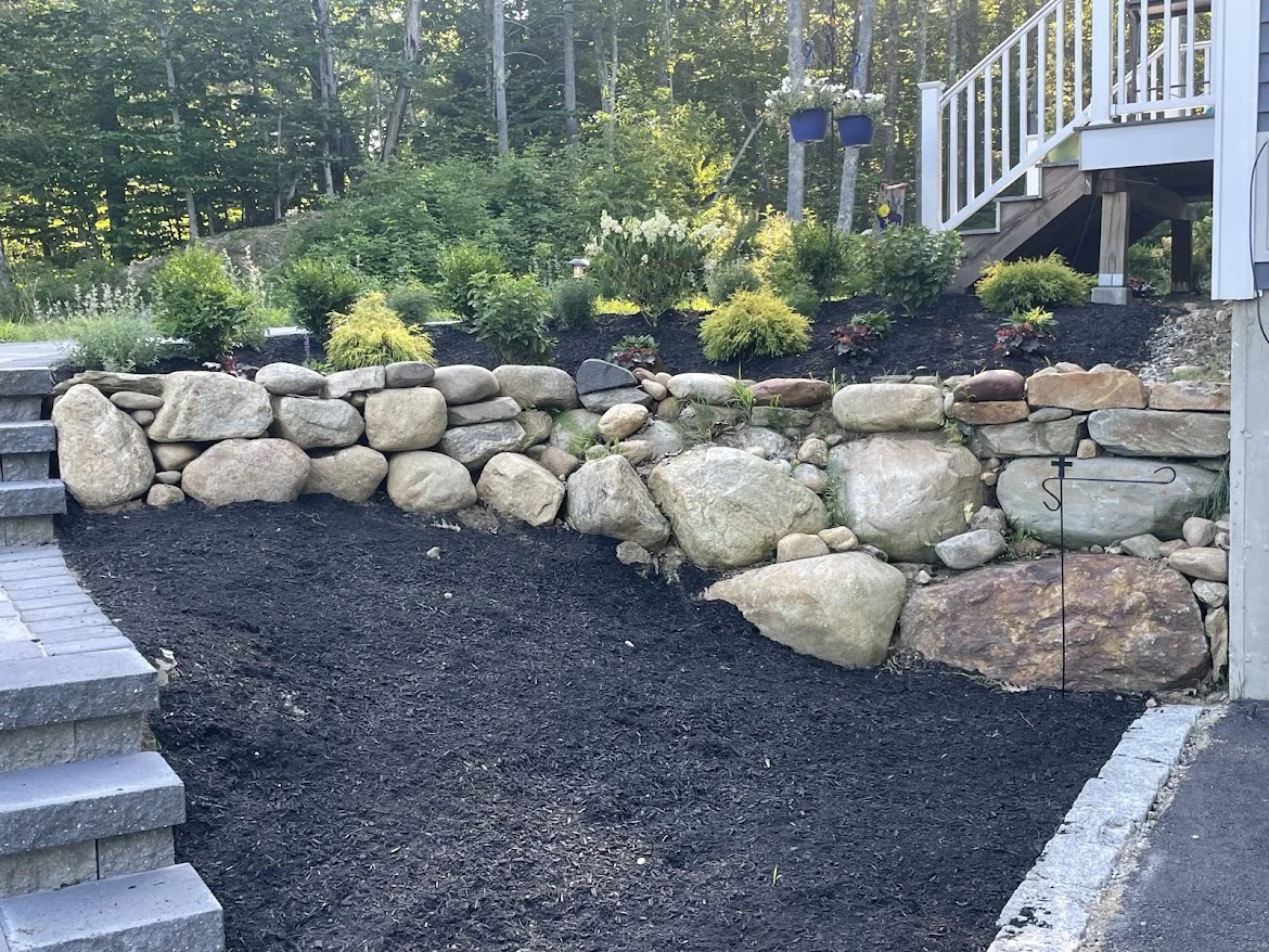 Boulder retaining wall with terraced planting beds built by Up North Scapes