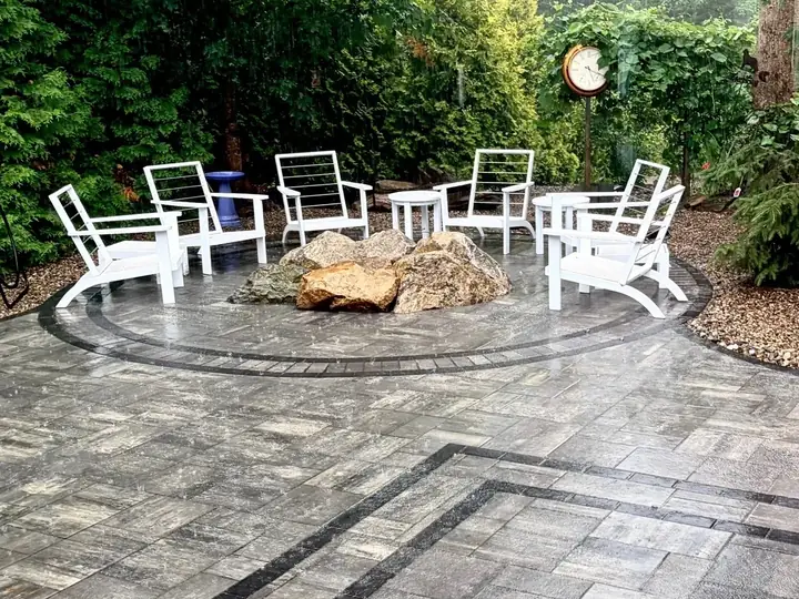 Paver patio with a circular inlay and a boulder fire feature at the center