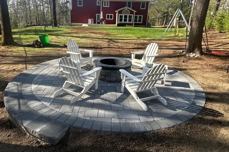 Round paver patio with a border band built around a fire pit, built by Up North Scapes