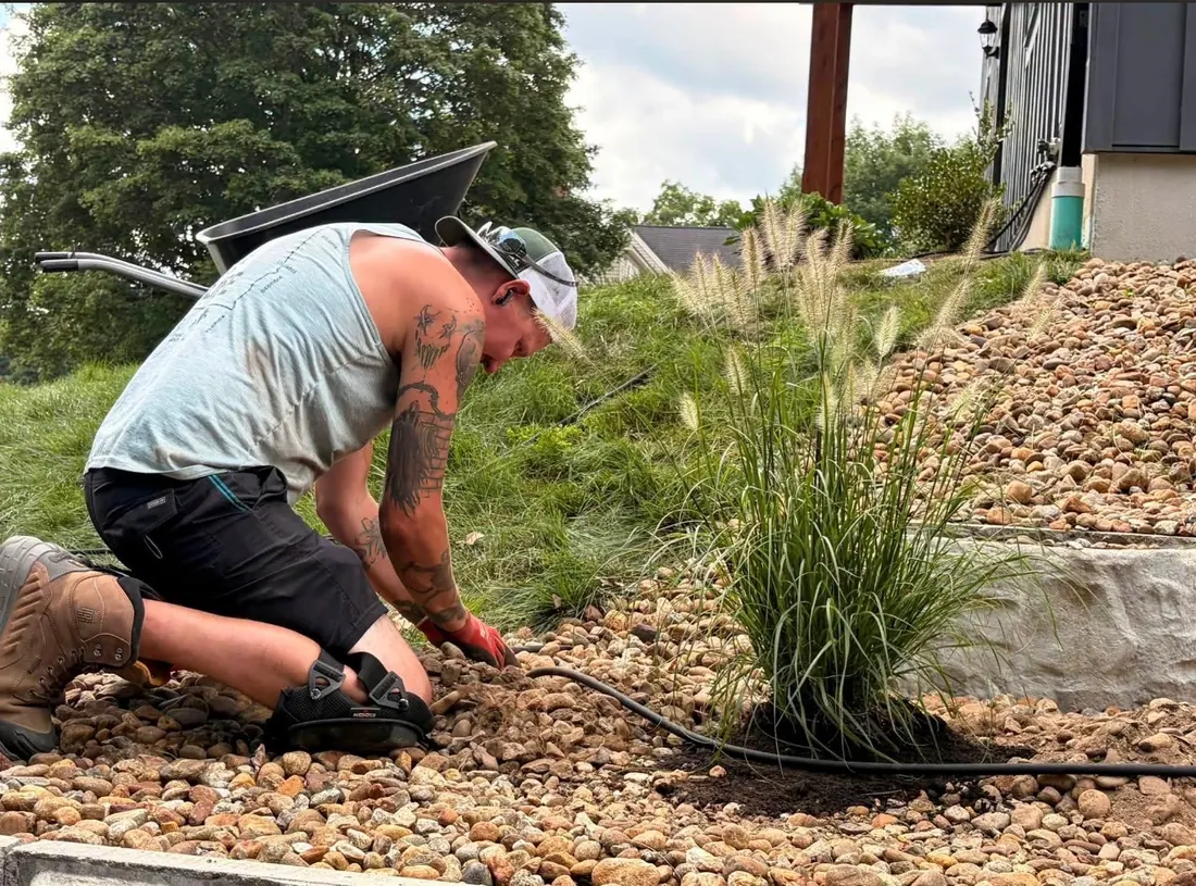Up North Scapes crew member installing plantings and irrigation in a rock landscape bed