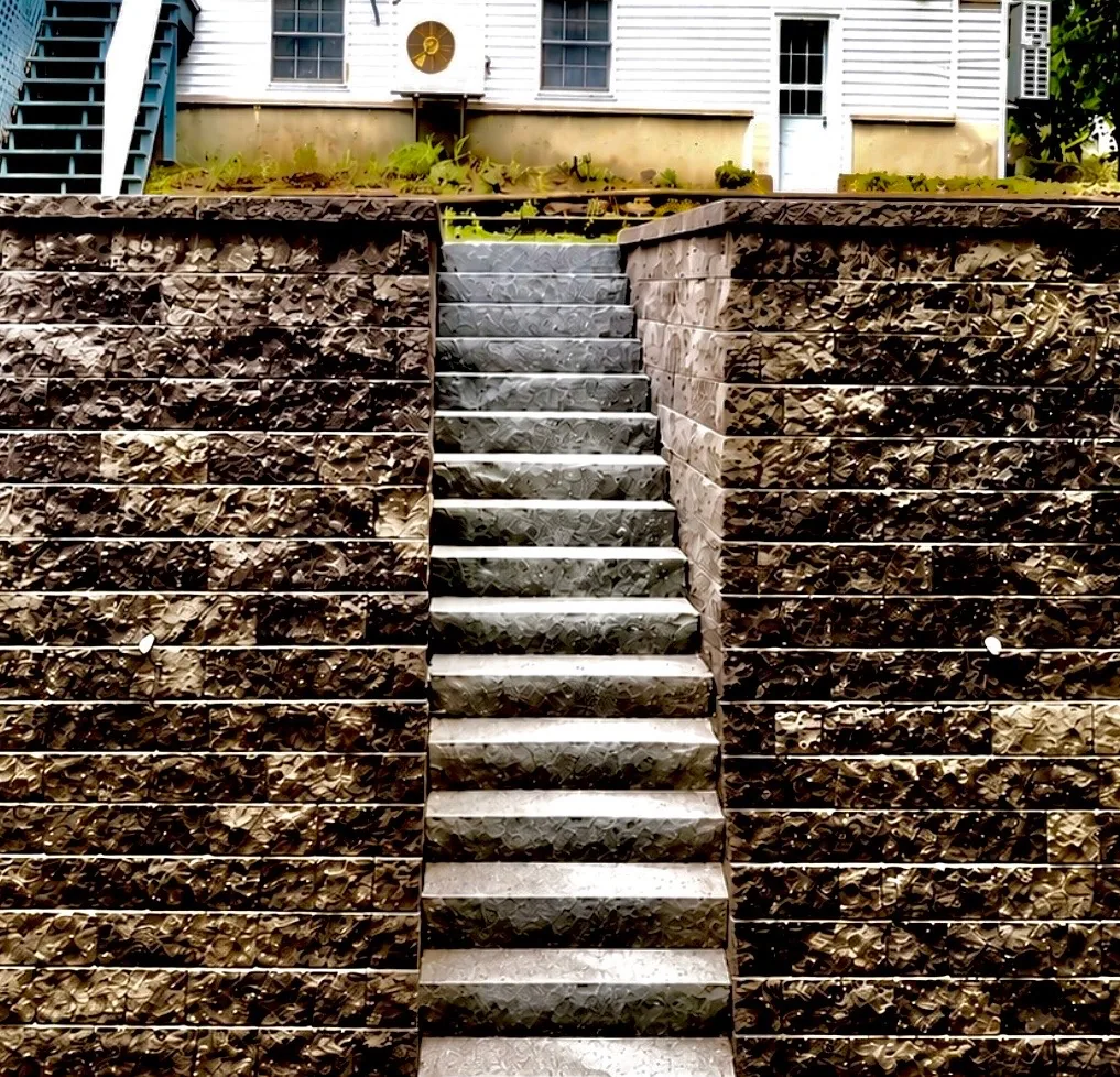 Tall block retaining wall with a full flight of granite stairs running through it