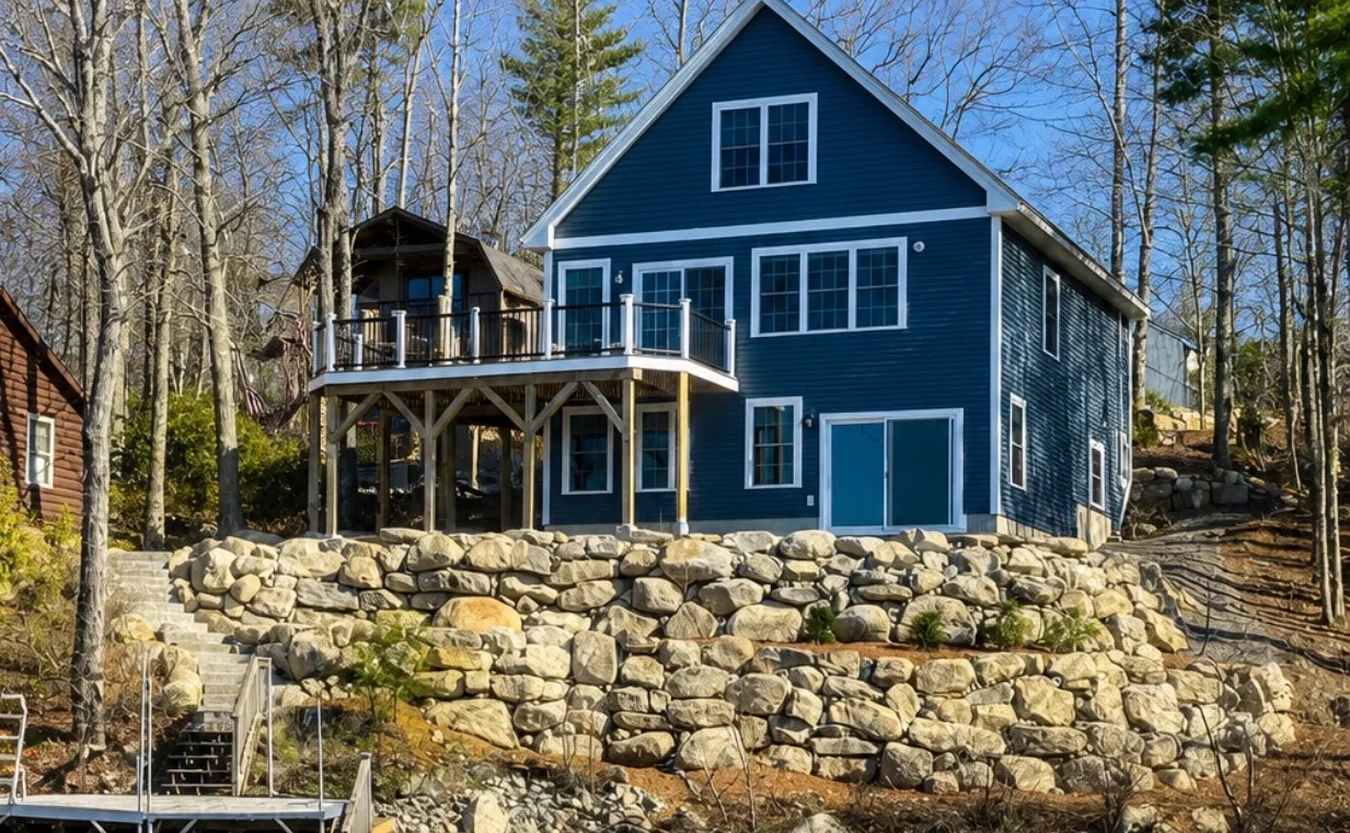 Waterfront boulder retaining wall holding the bank below a lakeside home in New Hampshire