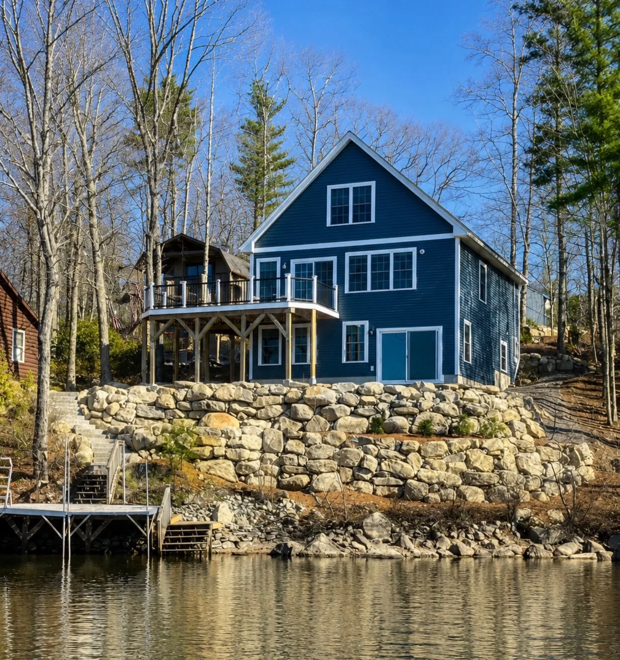 Boulder retaining wall holding a waterfront bank below a lake house