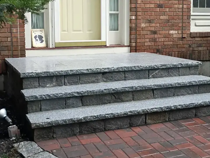 Granite slab steps with a granite cobble edge at a brick house