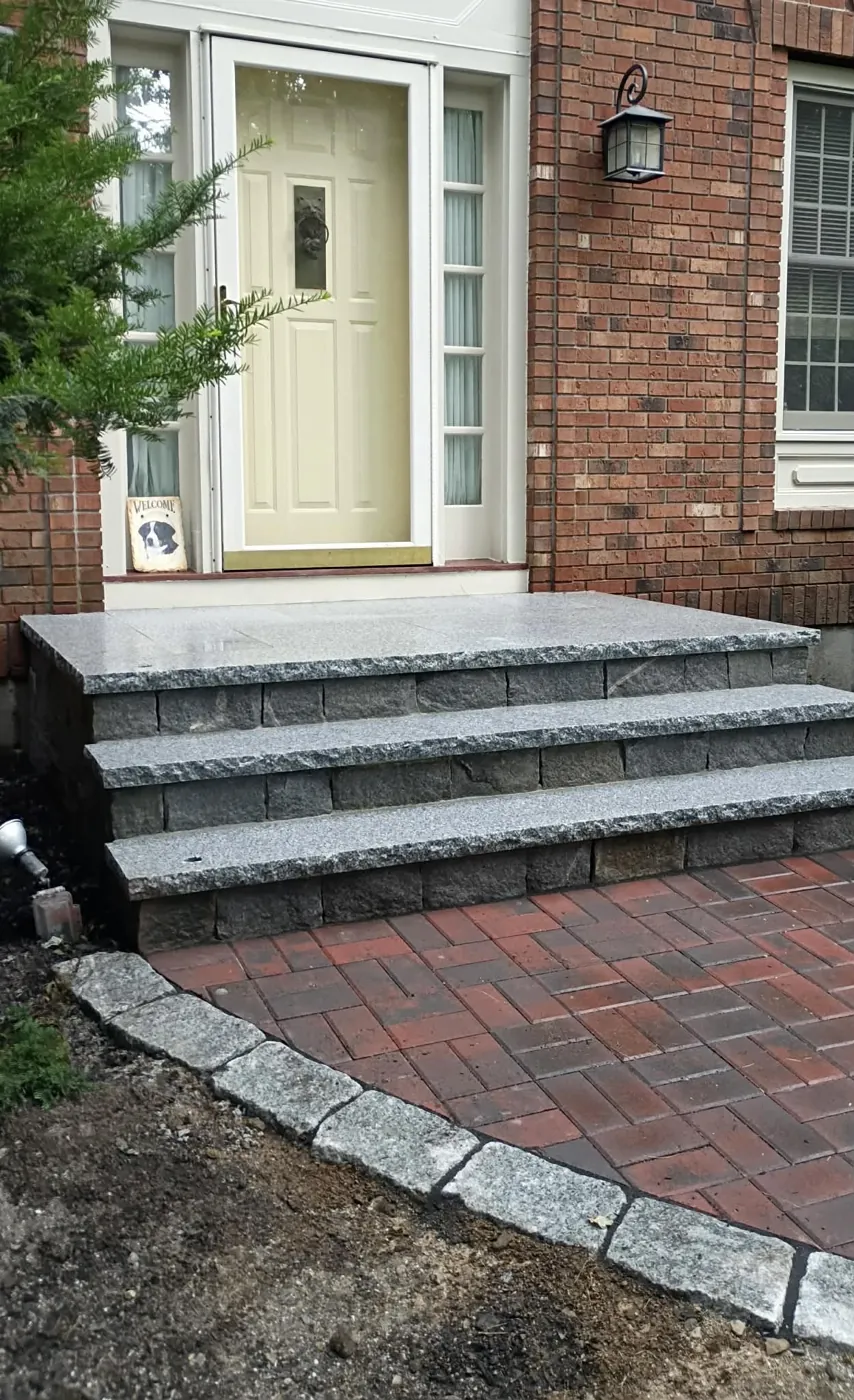 Granite slab steps with a granite cobble edge at a brick house