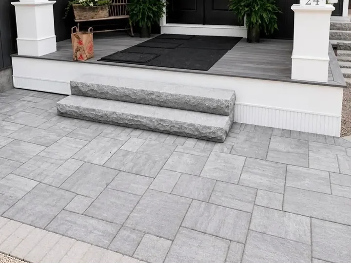 Granite steps rising from a gray paver landing to a porch