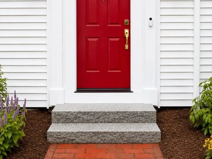 Granite steps up to a red front door with a brick walk below