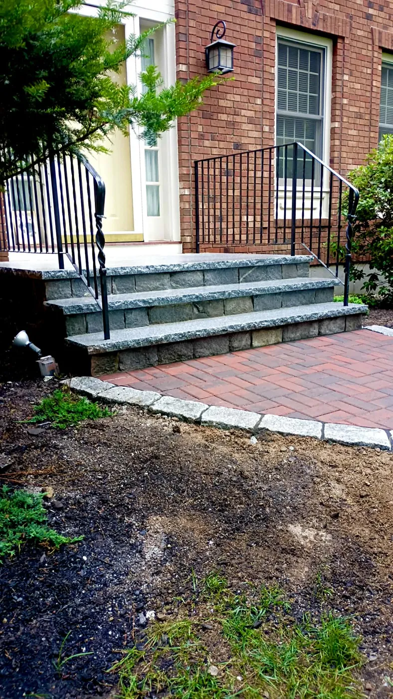 New granite steps with iron railings above a red paver walk at a brick house
