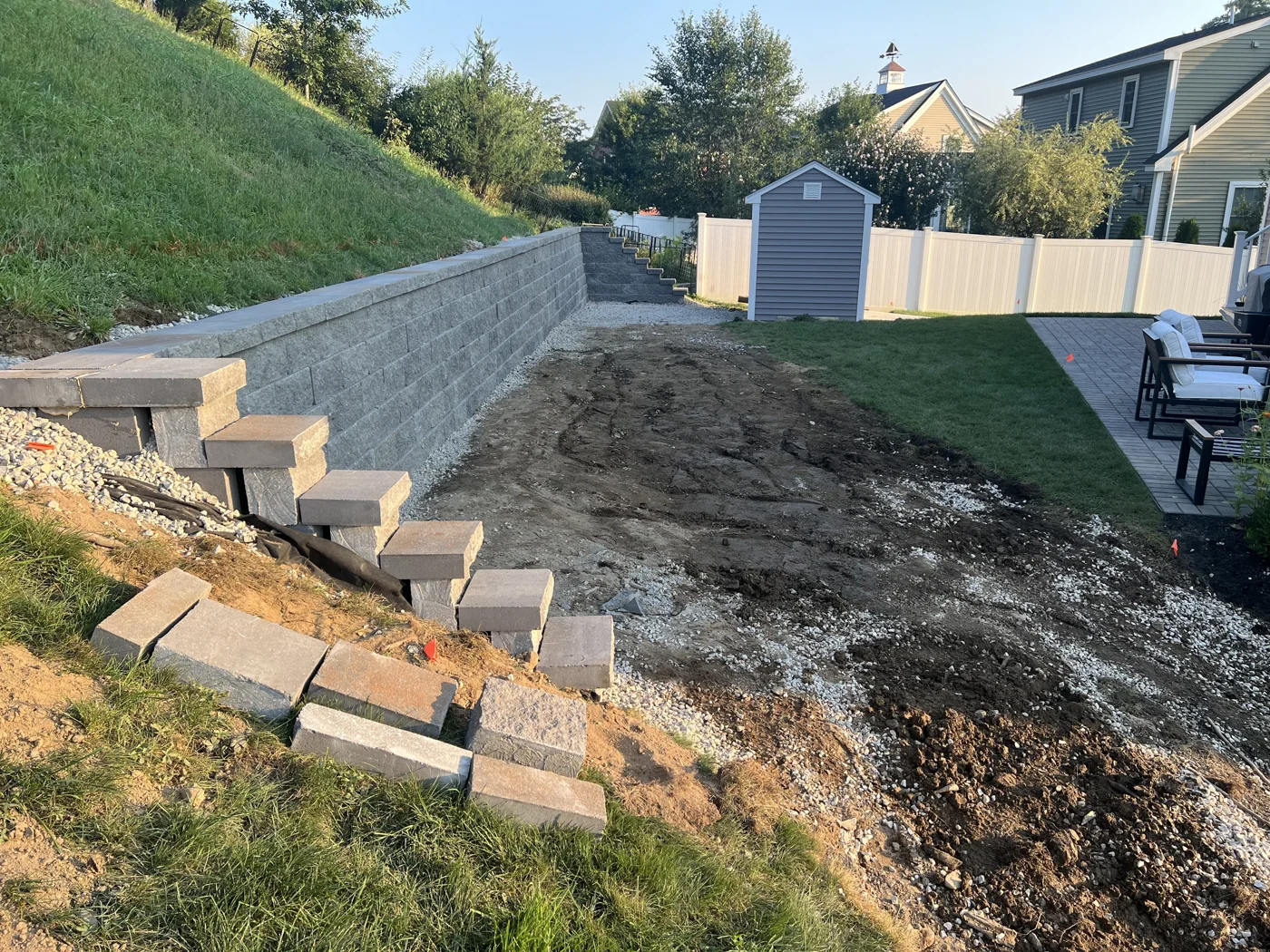 Block retaining wall standing with block steps being set into the slope