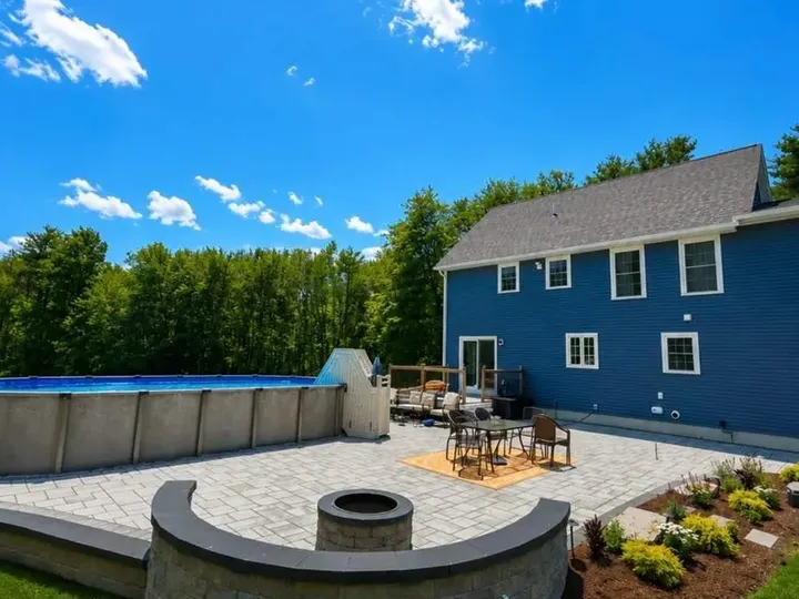 Paver patio with a curved seating wall and fire pit beside a pool