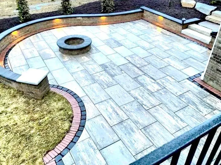 Paver patio with a curved seating wall, lights built into the cap and a fire pit