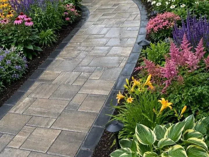Paver walk curving between perennial beds with path lights