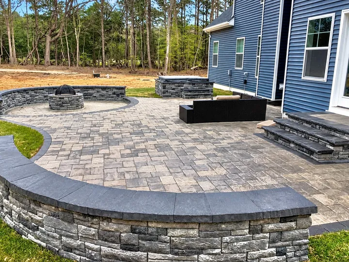 Curved block seating wall around a paver patio, with steps down from the house