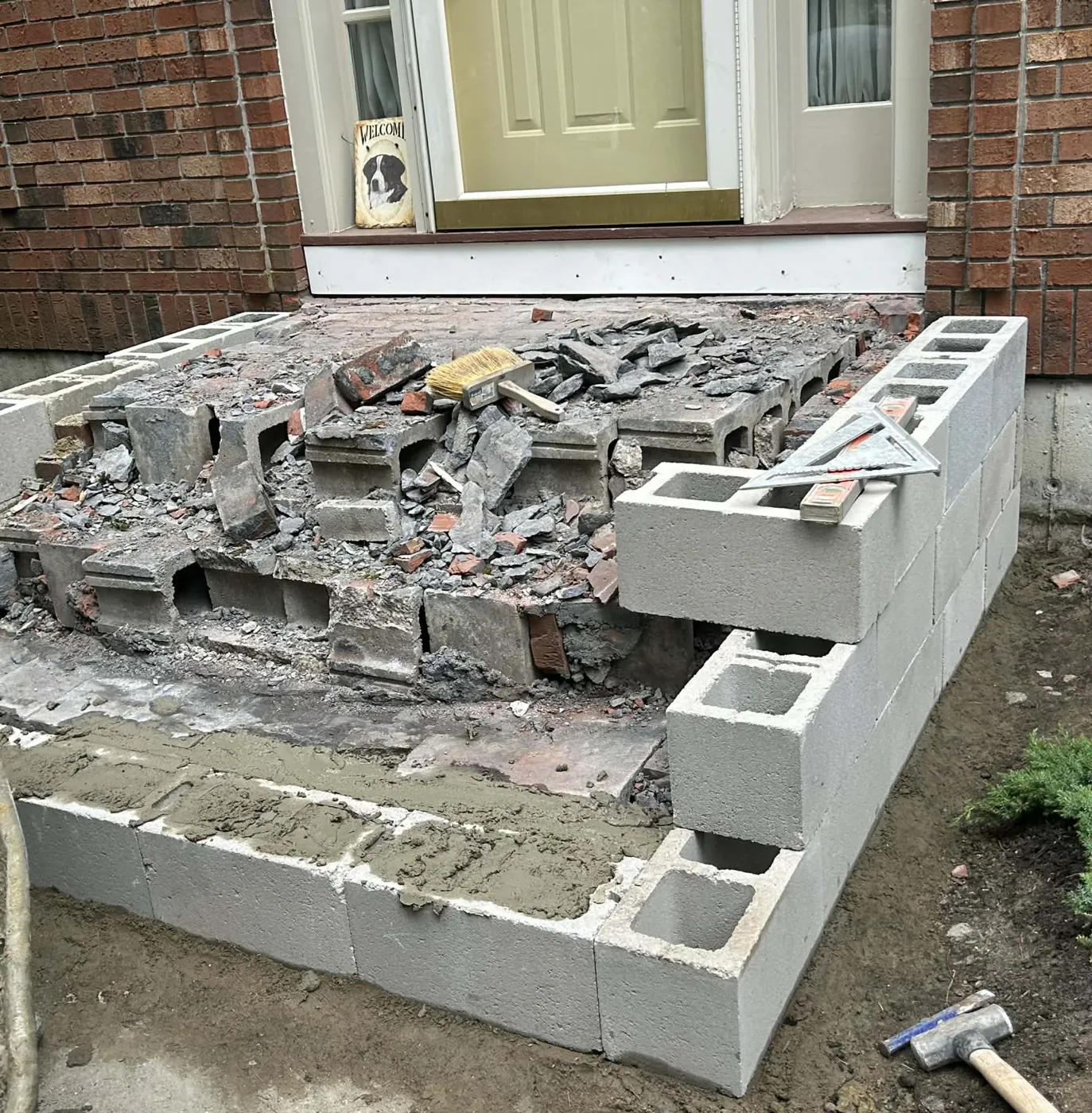 Old front steps broken out, with the concrete block core showing
