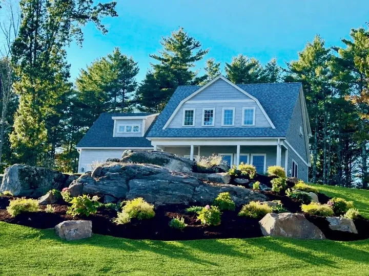 The same corner after the cleanup, with new beds and shrubs around a rock ledge