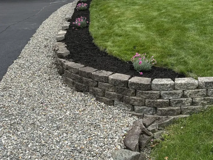 Planted bed above a stone wall by a driveway