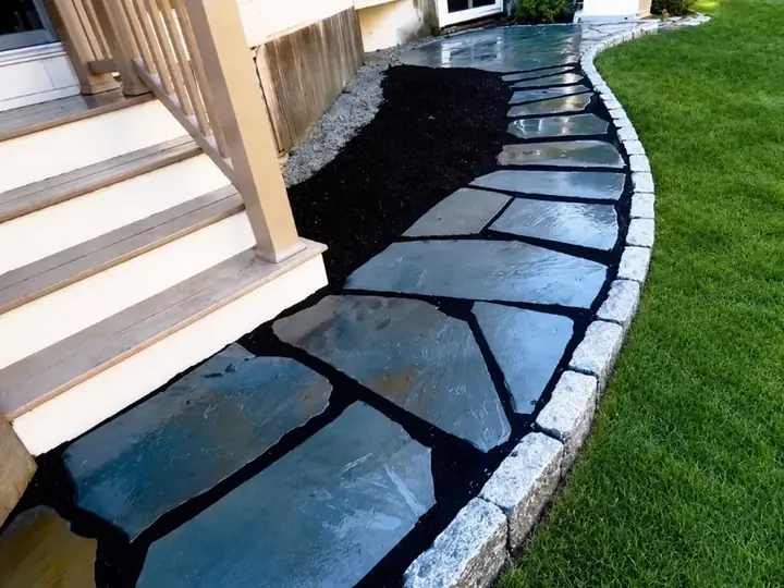 Bluestone walkway with a granite cobble edge curving past front porch steps