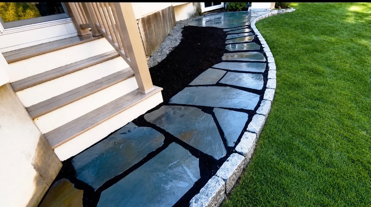Irregular bluestone walkway with a granite cobblestone edge curving along a lawn