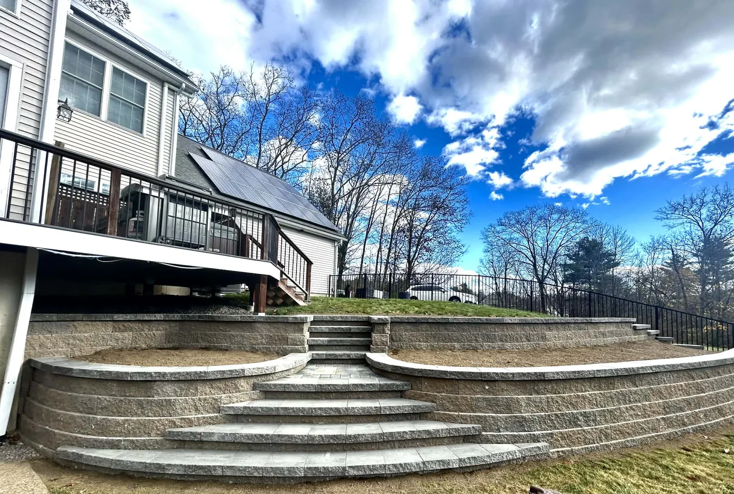 Two block retaining walls stepped back from each other with granite steps between the levels