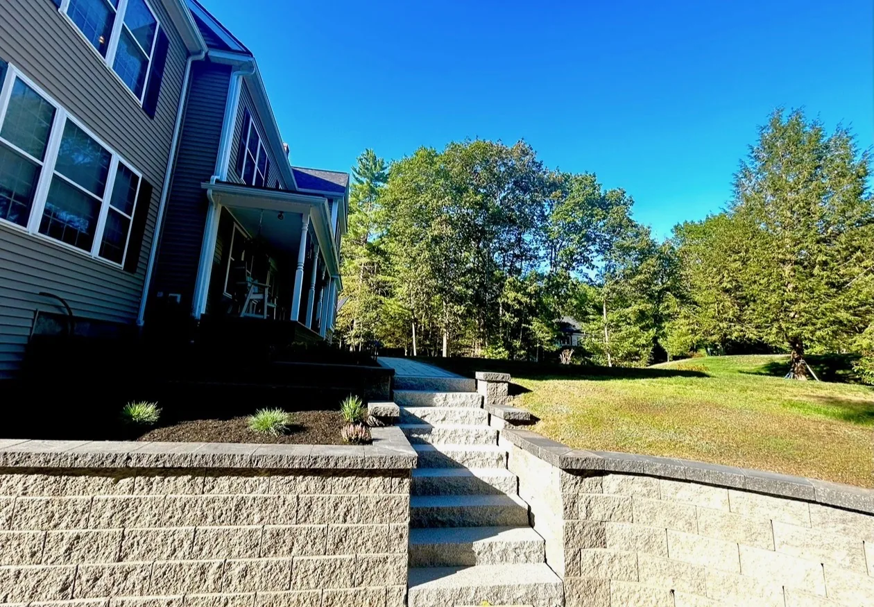Granite steps running down beside a block wall to a lawn