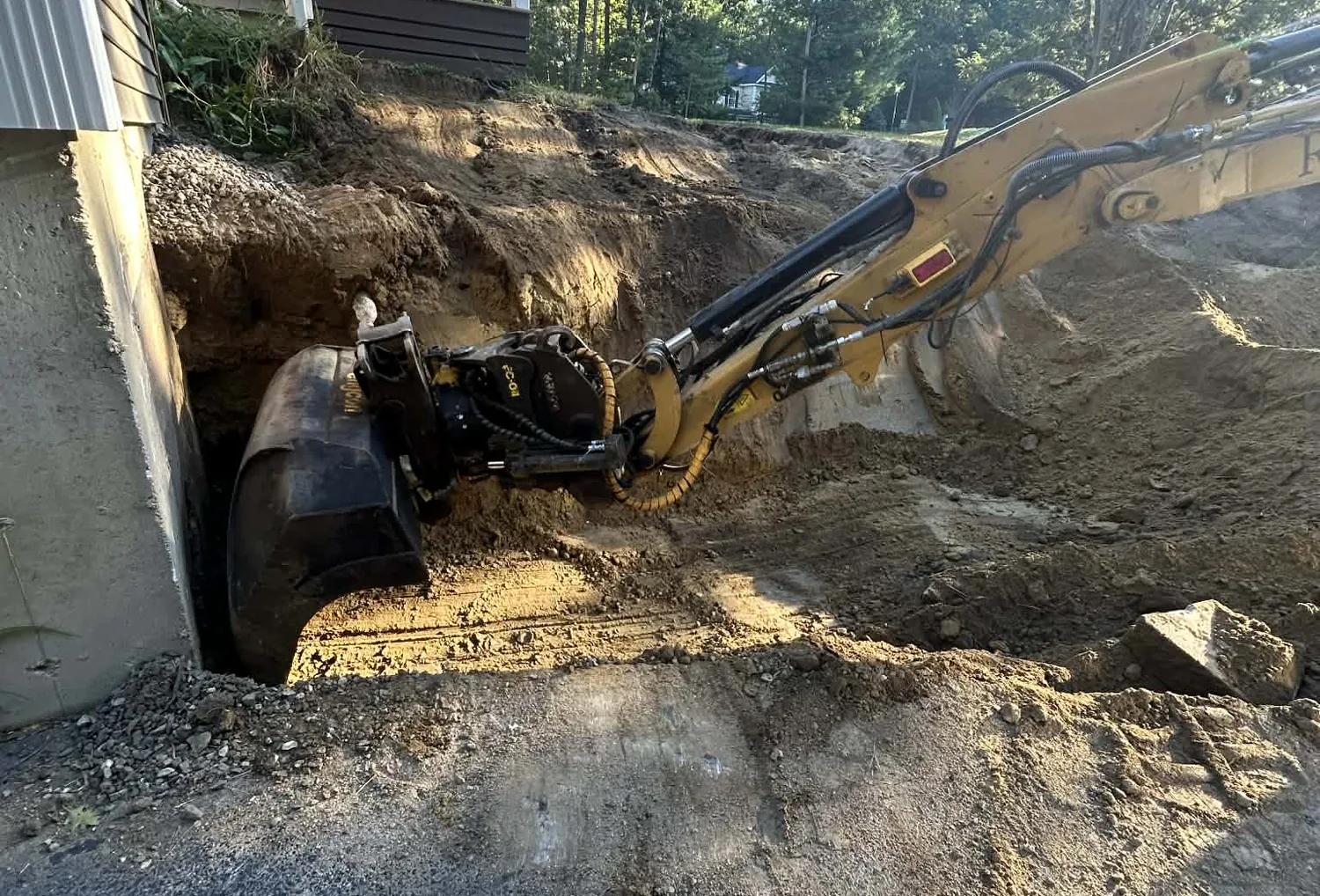 Excavator cutting a bank back to solid ground before a retaining wall goes in