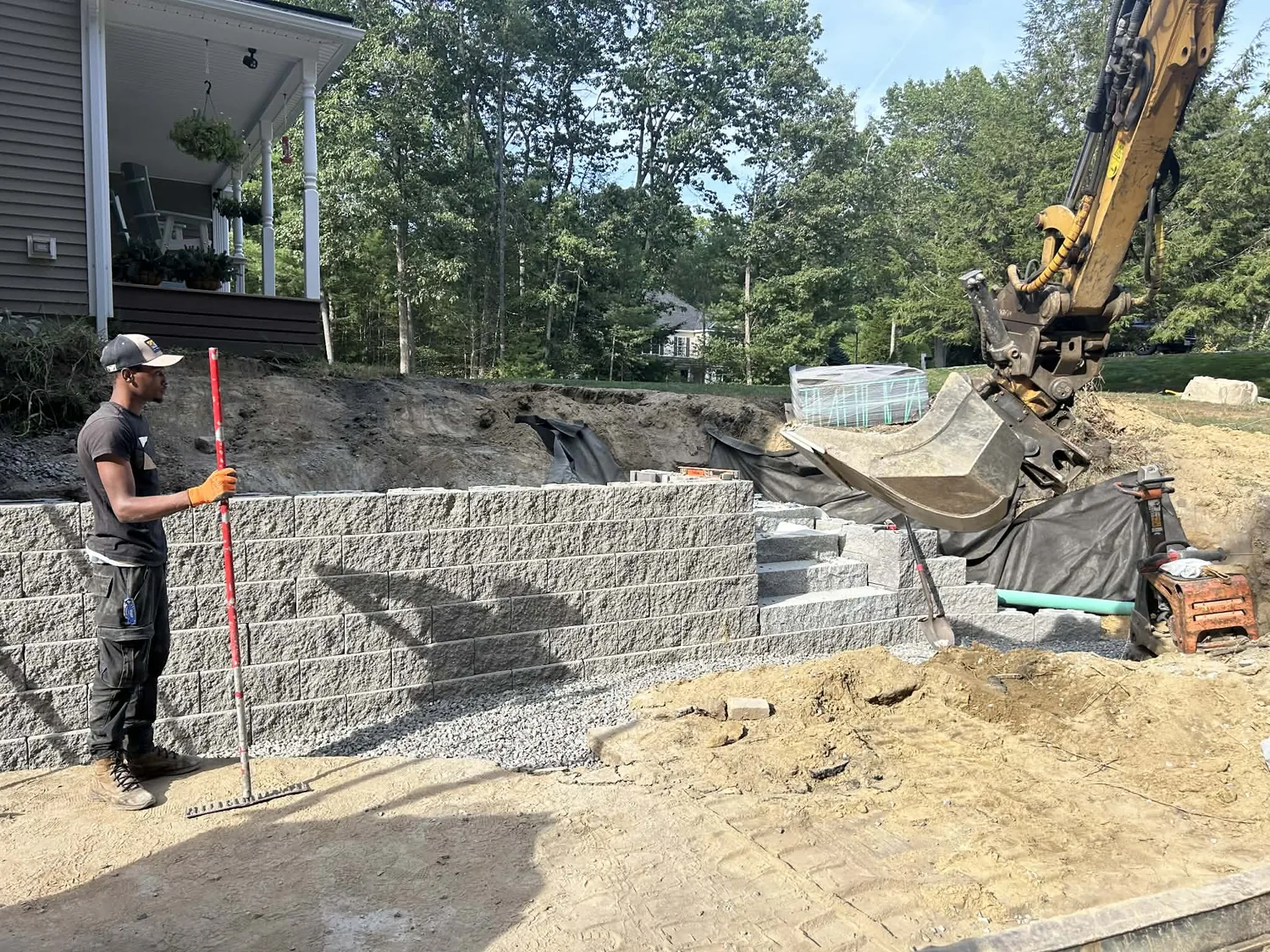 Drainage stone and pipe going in behind a retaining wall before it is buried