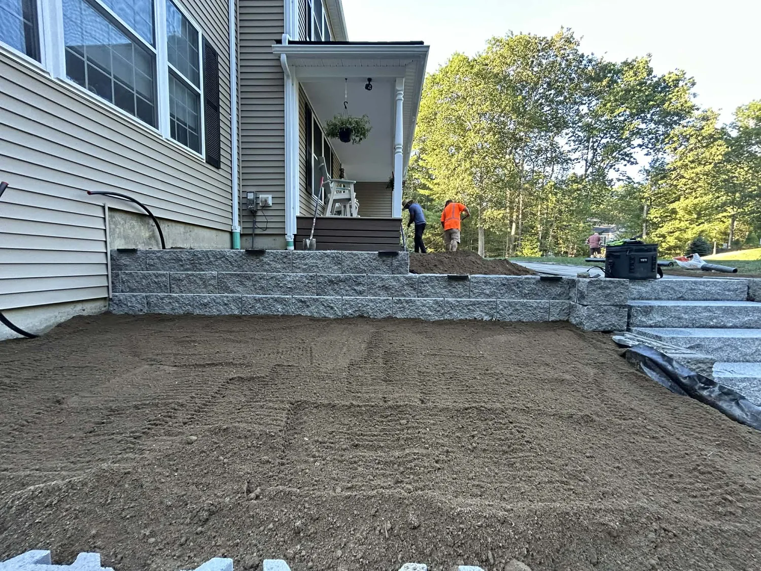 Finished retaining wall and granite steps with the yard graded and ready for loam