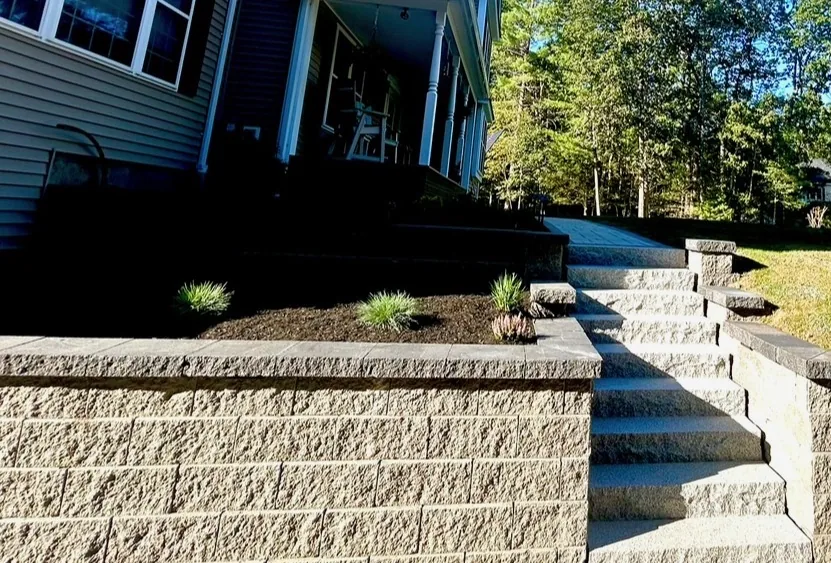 Finished tiered block retaining wall with a cap course, granite steps and mulched planting beds