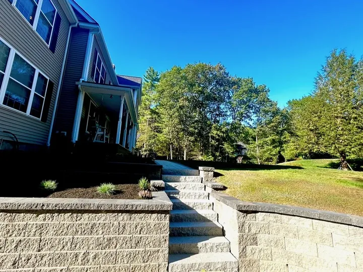 Block retaining wall with steps beside a house, planted along the top